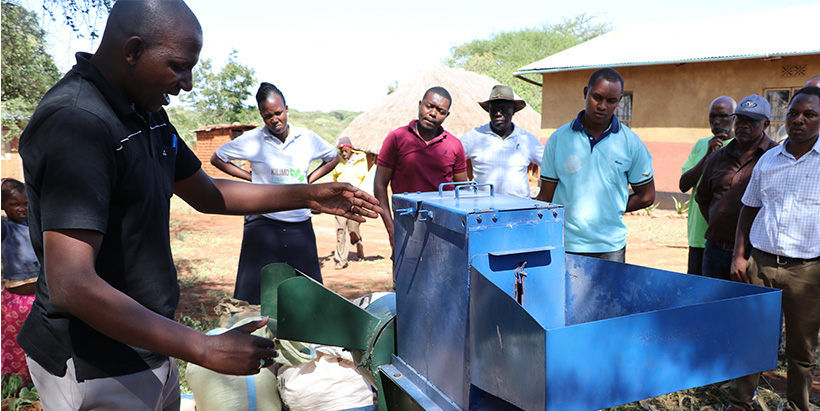 A scientist, Christopher Mutungi trains farmers how the newly developed low-cost mechanized multi crop processor prototype works at Changarawe Village in Karatu District.