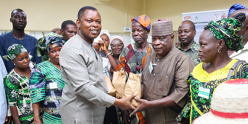 Dr Olugboyega Pelemo handing over yam seeds to participating farmers at the Outreach.
