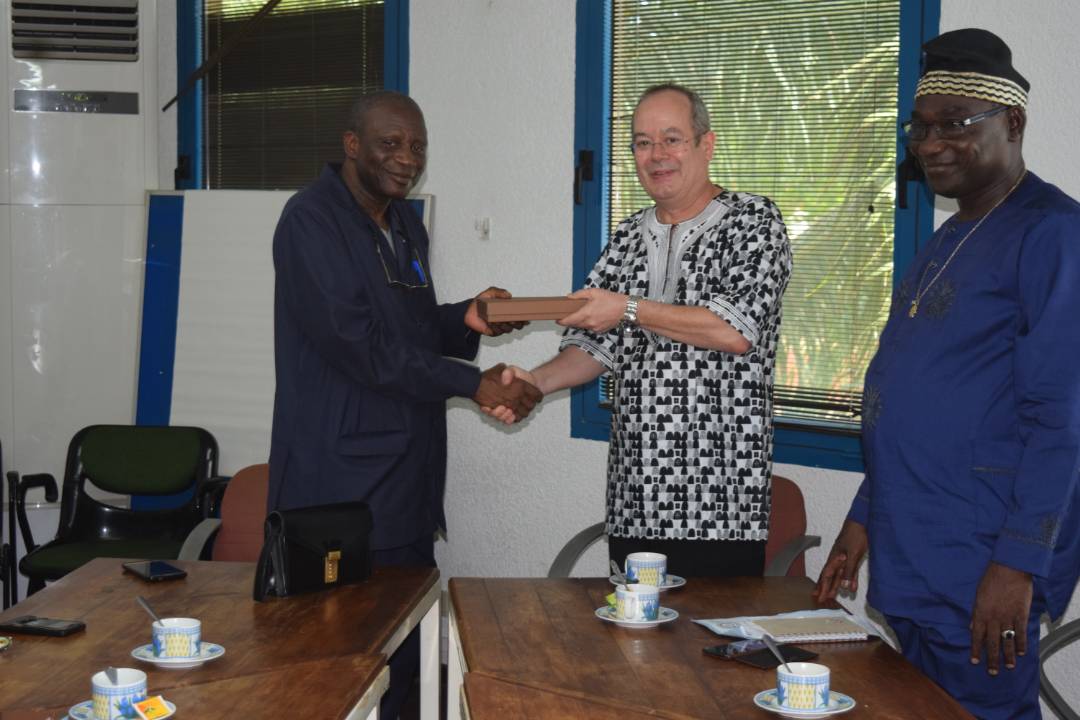 Picture of IITA-Benin Country Representative Manuele Tamo presents a token to UNA Vice-Chancellor, Professor Gauthier Biaou