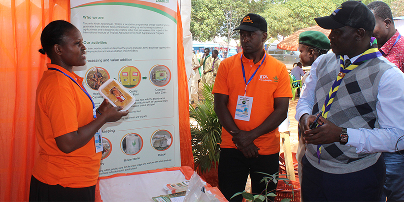 IITA executive Ass. Director’s office, Veronica Kebwe showing one of the cakes made by a group of trained youth in front of Malinyi District Commissioner, Mathayo Maselle. Photo: Hadi/IITA