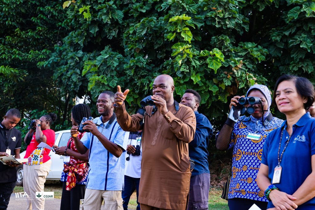 Rotary International President Elect (RIPE), Olayinka Babalola sights the pied kingfisher with his binoculars during the birdwatching exercise, guided by the Head of IITA Forest Center, Adewale Awoyemi, in the company of other Rotarians, the Head of Communication, Kathy Lopez and IITA staff.
