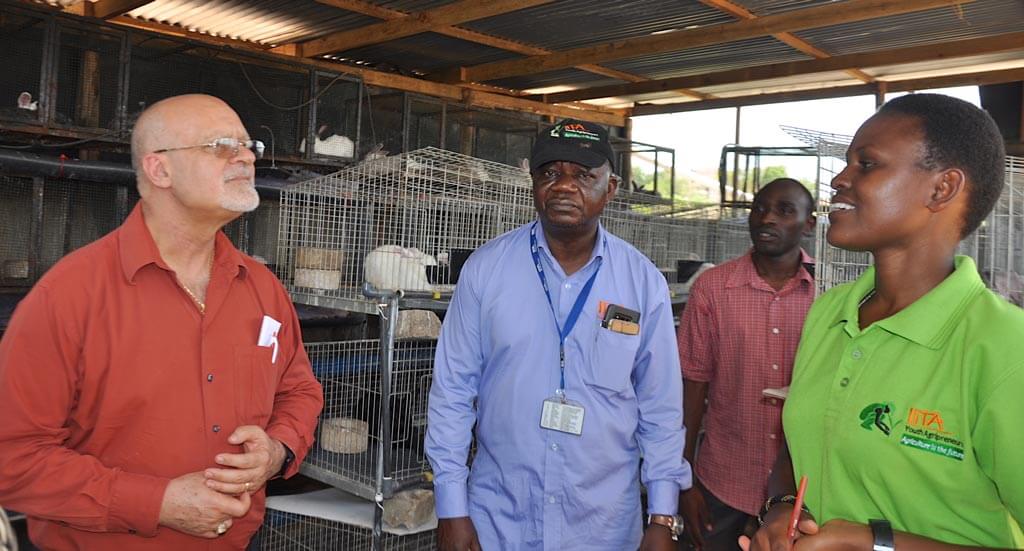 Picture of Ken Dashiell listening to the Veronica Kebwe, the Enable Youth Coordinator in Tanzania explaining the youth’s rabbit keeping project.