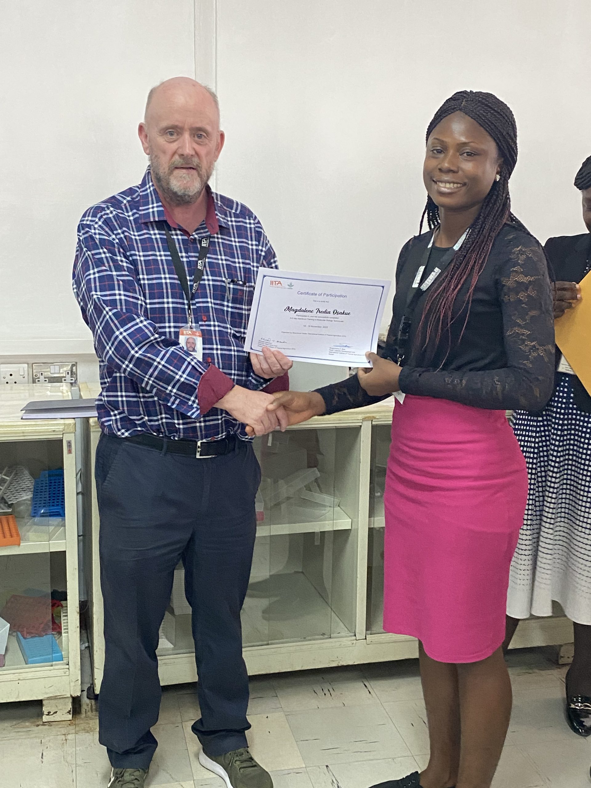 An intern, Magdalene Osakue, receiving her certificate from Michael Abberton.