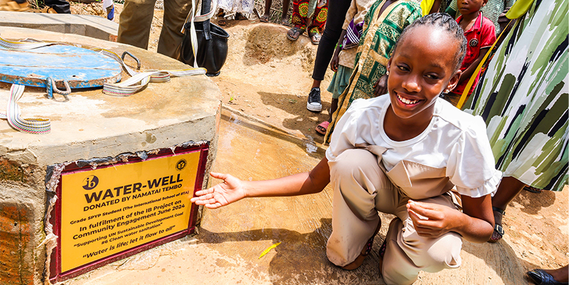 Namatai Tembo poses at the well with her gift of love and dedication to the Aleelo Community.