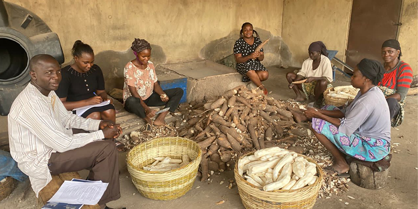 Obafunsho (middle) and some team members—Olamide Olaosebikan (writing) and Bello Abolore (Male), with women peeling cassava in a gari processing center in Idi-Iroko Community in Osun State.