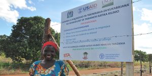 A farmer next to the poster of the demonstration plots established by the project.