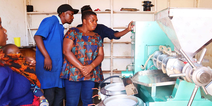 Processors learning how to use one of the cassava milling machines.