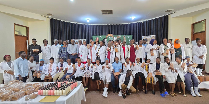Trainees graduate and pose to showcase the soy-based products they made.