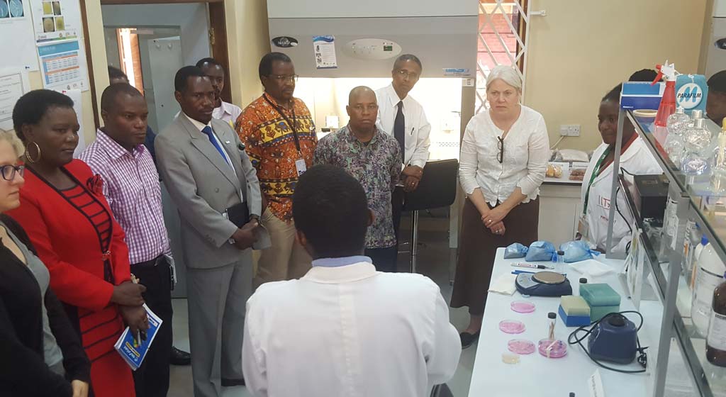 Picture of Jocelyn Brown (second from right) listens to a technician’s briefing during the lab visit.